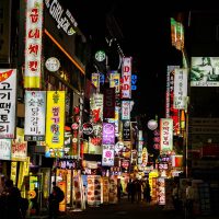 韩国影库主编在书桌前核对韩国电影在线观看片单资料，手边放着标注年份与导演的纸质清单，环境安静